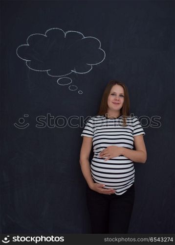young pregnant woman thinking about names for her unborn baby to writing them on a black chalkboard. pregnant woman thinking in front of black chalkboard