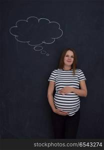 young pregnant woman thinking about names for her unborn baby to writing them on a black chalkboard. pregnant woman thinking in front of black chalkboard