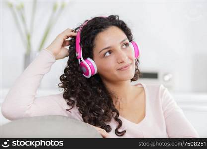 young pregnant woman with headphones on the sofa