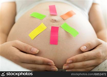 Young pregnant woman with memo sticker on belly