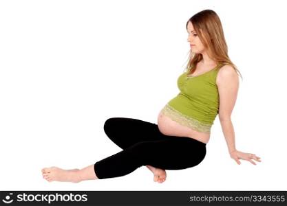 Young pregnant woman with pensive look sitting on the ground, isolated over white background.