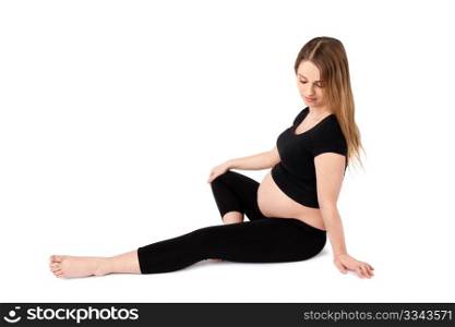 Young pregnant woman with pensive look sitting on the ground, white background.
