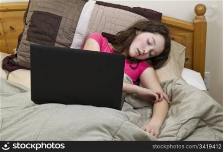 Young Preteen Asian girl falls asleep with laptop while in bed
