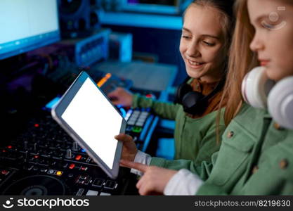 Young preteen girls band adjusting sound on sound mixer in radio station or record studio. Young girls adjusting sound on sound mixer in radio station