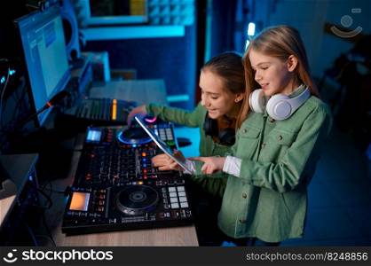Young preteen girls band adjusting sound on sound mixer in radio station or record studio. Young girls adjusting sound on sound mixer in radio station