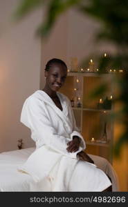 Young pretty african woman sitting at beauty spa salon wearing bathrobe