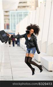 Young pretty black woman jumping in the street with a briefcase