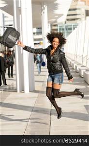 Young pretty black woman jumping in the street with a briefcase