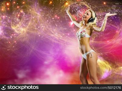 Young pretty blonde in bikini dancing with headphones on head. Beach party