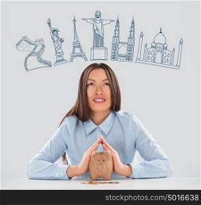 Young pretty business woman dreaming about vacation and saving money with piggy bank for her trip to famous touristic destination. Architecture symbols overhead