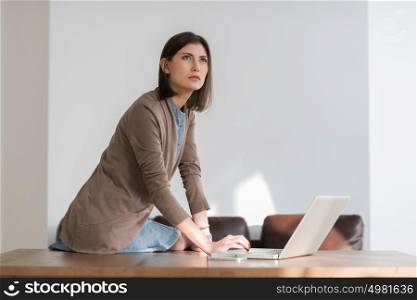 Young pretty business woman working with laptop in the office looking away pensive