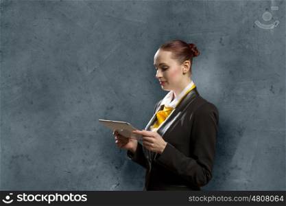 Young pretty businesswoman against grey background using tablet pc. Woman with tablet pc