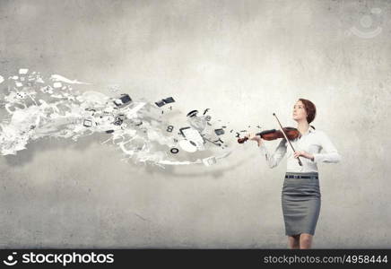 Young pretty businesswoman on cement background playing violin. My business melody