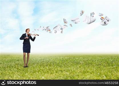 Young pretty businesswoman playing violin and papers flying in air. My business melody
