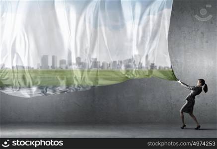 Young pretty businesswoman pulling clothing banner with city scene. Woman pull curtain