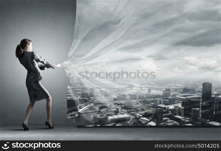 Young pretty businesswoman pulling clothing banner with city scene. Woman pull curtain