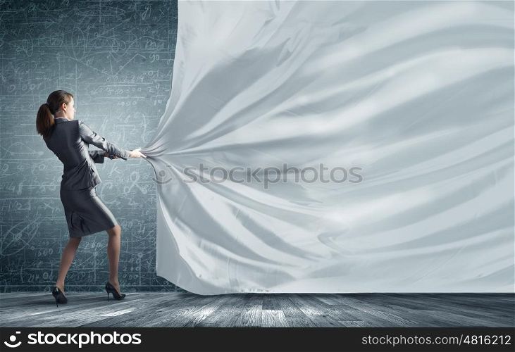 Young pretty businesswoman pulling white blank banner. Place for your advertisment