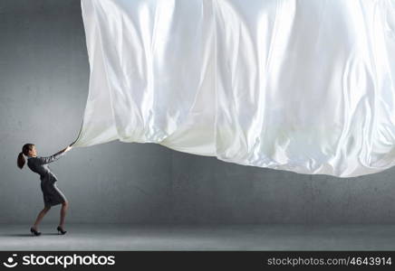 Young pretty businesswoman pulling white blank banner. Woman pull curtain