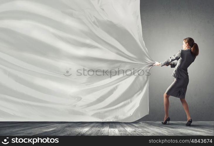 Young pretty businesswoman pulling white blank banner. Woman pull curtain