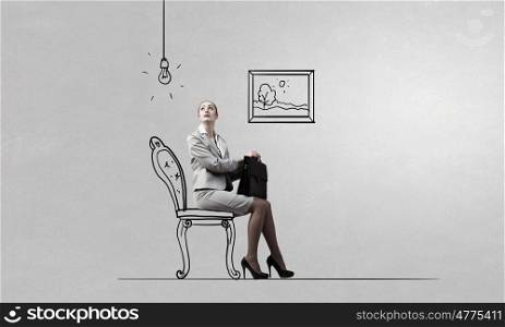 Young pretty businesswoman sitting on chair with briefcase in hands. Taking break from office