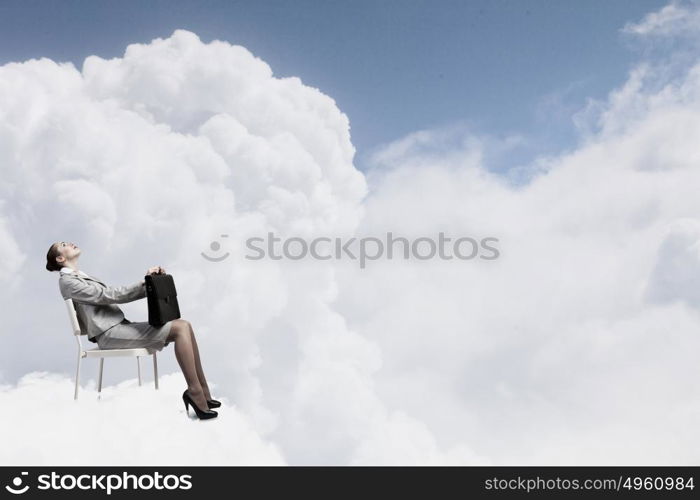 Young pretty businesswoman with briefcase in hands sitting on cloud . Taking break from office