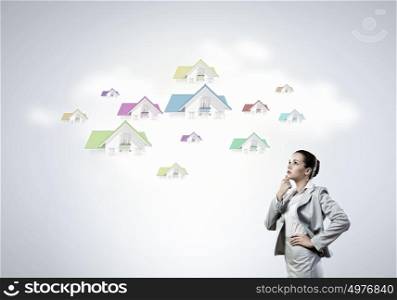 Young pretty businesswoman with houses over head. Thoughtful businesswoman