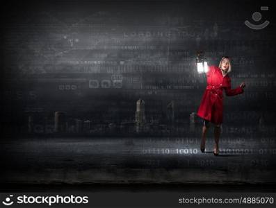 Young pretty businesswoman with lantern in darkness. Lost in darkness