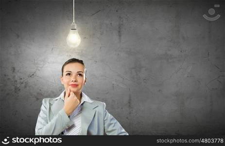 Young pretty businesswoman with light bulb over head. Thoughtful businesswoman