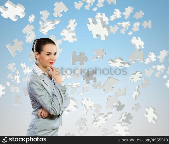 Young pretty businesswoman with puzzle elements over head. Thoughtful businesswoman
