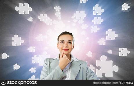 Young pretty businesswoman with puzzle elements over head. Thoughtful businesswoman