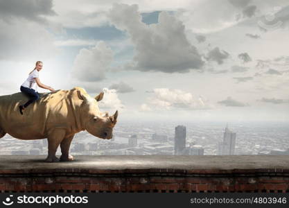 Young pretty fearless woman riding huge rhino. Woman ride rhino