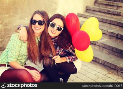 Young pretty hipster girls friends having fun outdoor in summer on the street. Vintage lifestyle trendy portrait.