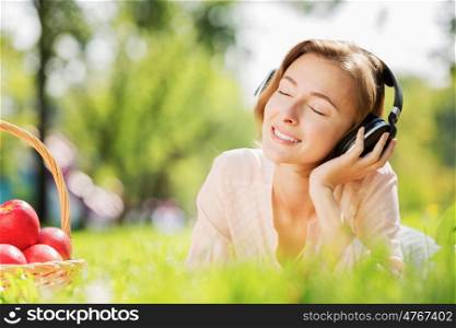 Young pretty lady in park listening to music. Sunny weekend in park