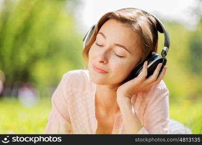 Young pretty lady in park listening to music. Sunny weekend in park