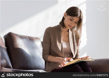 Young pretty lady sitting on couch at home or office thinking about something and planning