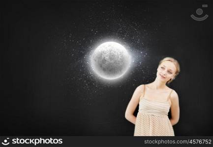 Young pretty smiling woman at blackboard looking at moon. Astronomy study