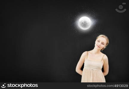 Young pretty smiling woman at blackboard looking at moon. Astronomy study