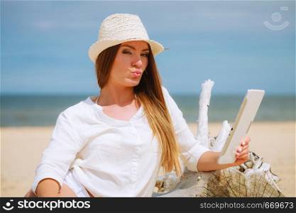 Young pretty sweet woman with tablet pc computer on beach. Technological resting, summer, vacation.