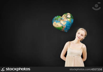 Young pretty woman and heart shaped Earth planet. Elements of this image are furnished by NASA. Environment lesson