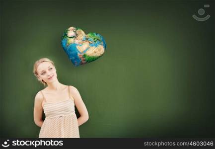 Young pretty woman and heart shaped Earth planet. Elements of this image are furnished by NASA. Environment lesson