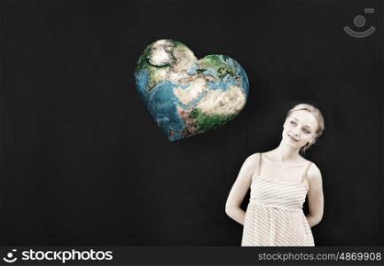 Young pretty woman and heart shaped Earth planet. Elements of this image are furnished by NASA. Environment lesson