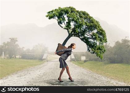 Young pretty woman carrying green tree in pot