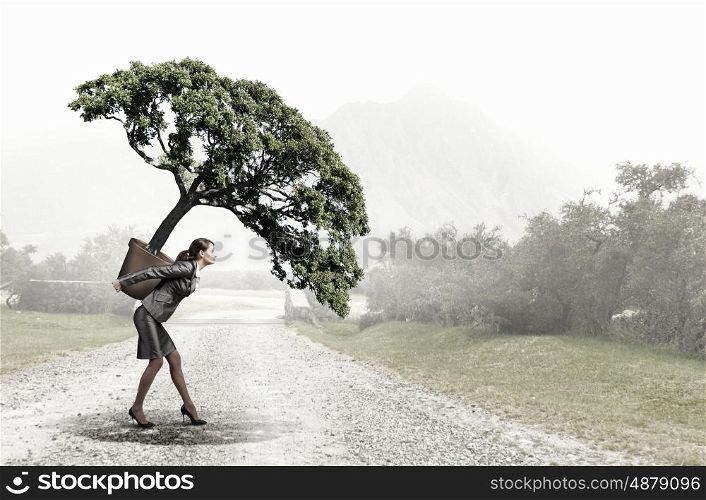 Young pretty woman carrying green tree in pot