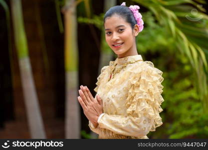 Young pretty woman dressed in beautiful Thai costumes, standing with hands folded in respect in temple on Songkran festival. Thai New Year, Family Day in April
