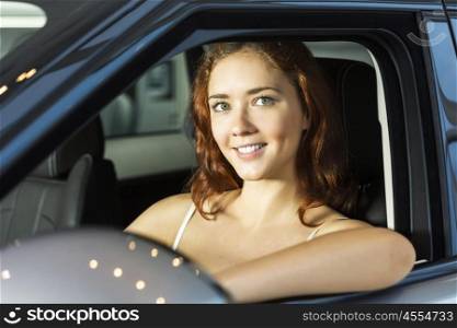 Young pretty woman in car salon sitting in car. My new car