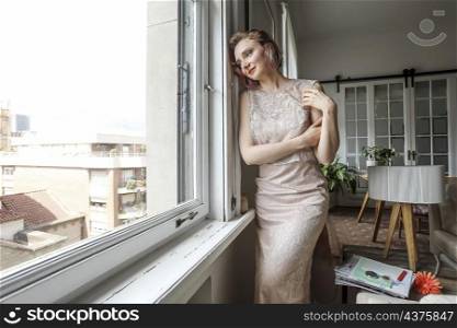 Young pretty woman in dress looking out the window