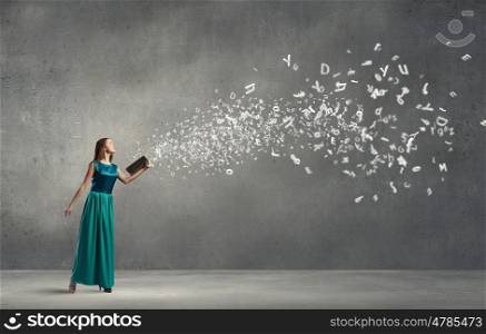 Young pretty woman in green dress with book in hands. Reading develops imagination