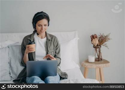 Young pretty woman in headset has online meeting at home. European girl in casual wear has coffee and internet conference. Homey girl having video call. Leisure and communication on quarantine.. Young pretty woman in headset has online meeting at home. Leisure and communication on quarantine.