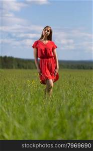 Young pretty woman in red dress against blue sky.