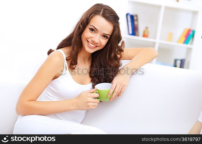 Young pretty woman in white at home sitting on the sofa